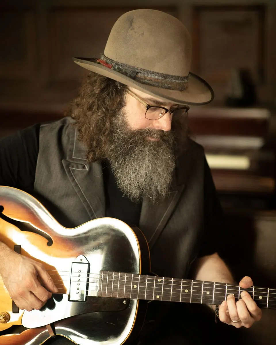 Bryce Alan Flurie wearing a hat and playing a guitar