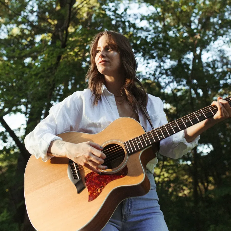 Natalie Tyer playing an acoustic guitar outdoors