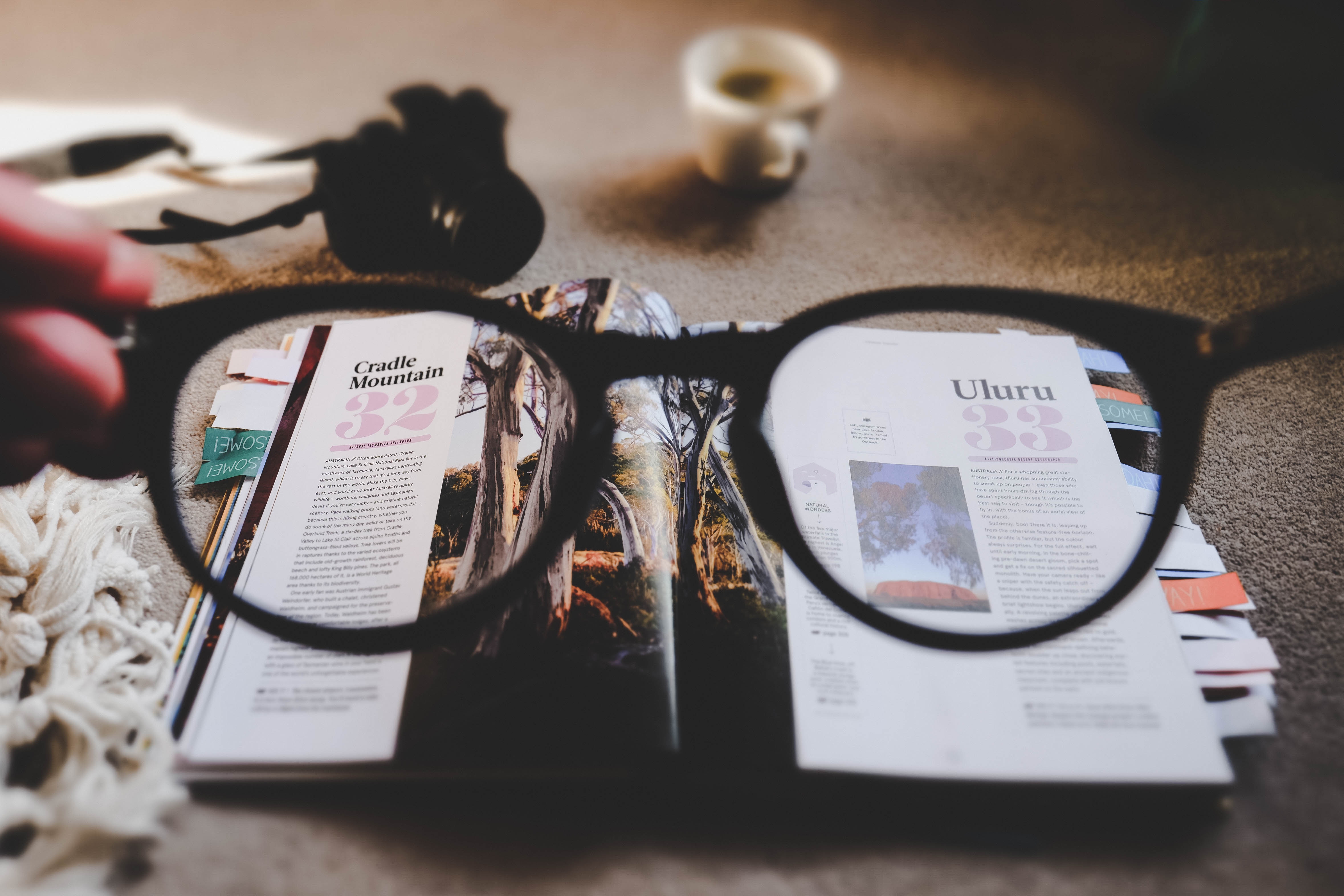 An open magazine viewed through glasses, with a camera nearby